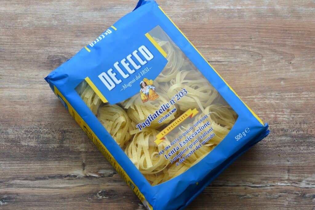 A packet of De Cecco tagliatelle on a wooden table.