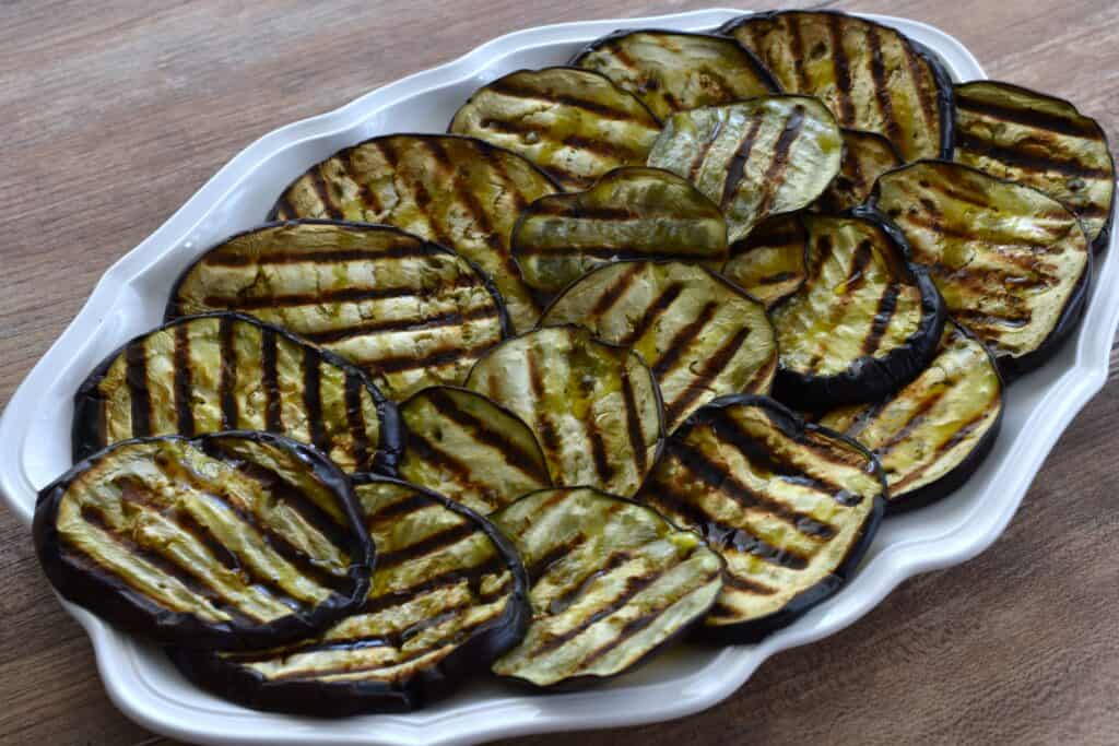 Grilled aubergines on a white oval serving platter.