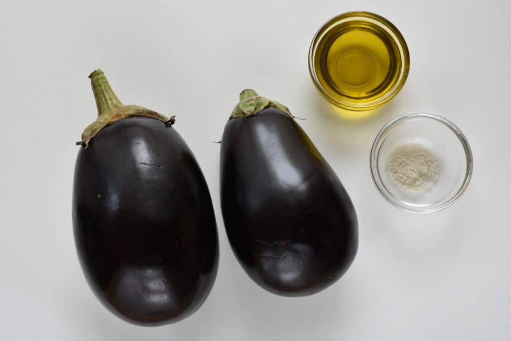 Two aubergines, olive oil and sea salt (ingredients for roasted aubergine slices)