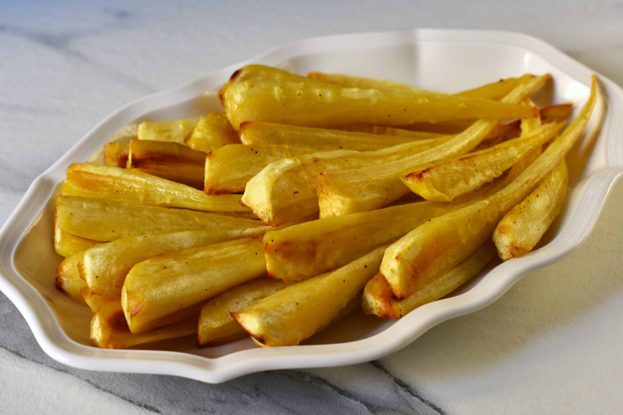 Oven-roasted parsnips on a white oval serving dish.