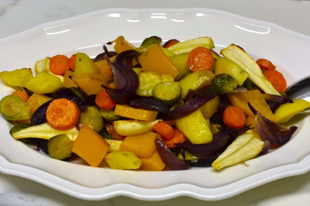 Oven-roasted winter vegetables on a white oval serving dish.