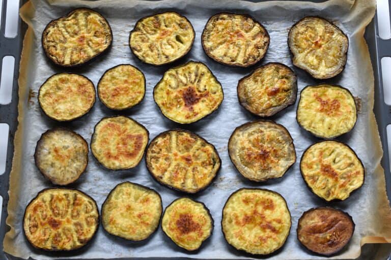 Roasted aubergine (eggplant) slices on an oven tray (first side).