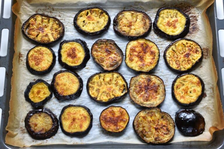 Roasted aubergine (eggplant) söices on parchment paper on a baking tray (2nd side).