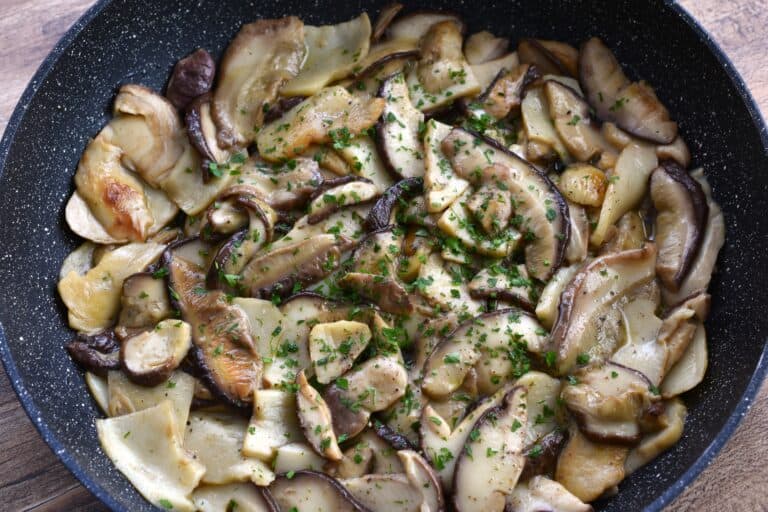 Sautéed porcini mushrooms in a frying pan with a garnish of fresh, chopped parsley.