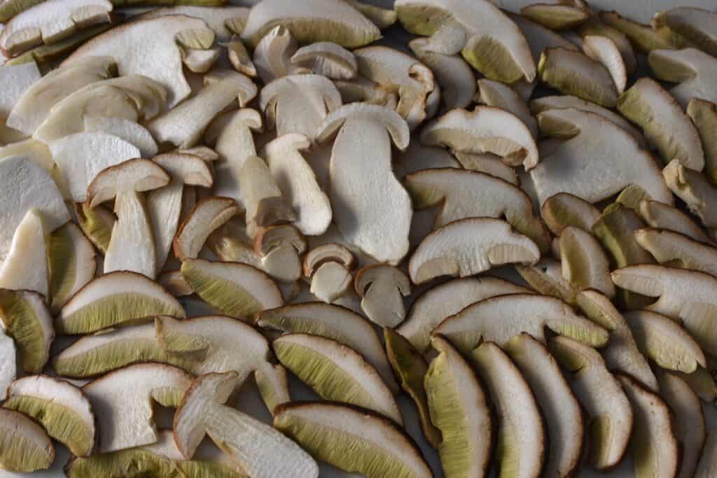 Porcini mushrooms sliced to a thickness of 1/2 cm on a worktop.