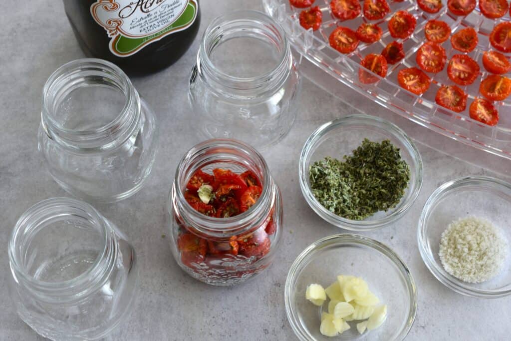 Jarring semi-dried cherry tomatoes with garlic, oregano, salt, and oil.