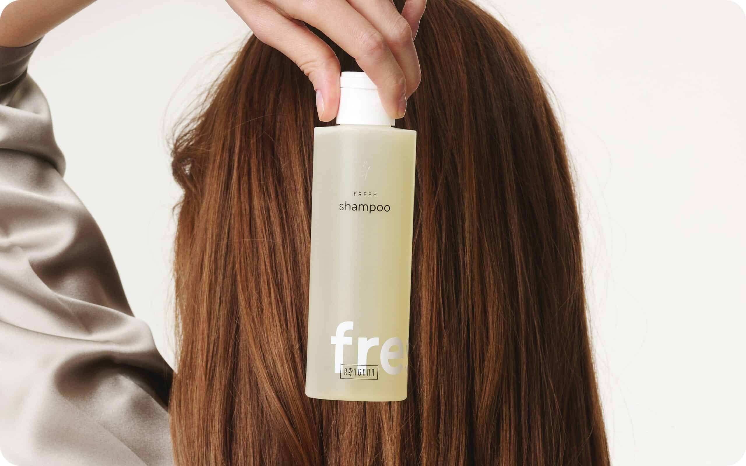 A model holding a bottle of Ringana vegan shampoo.