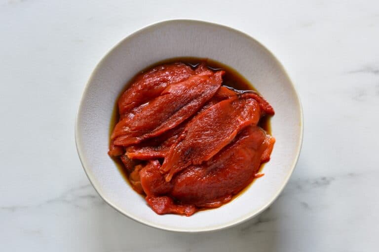 Roasted red pepper fillets in a white bowl.