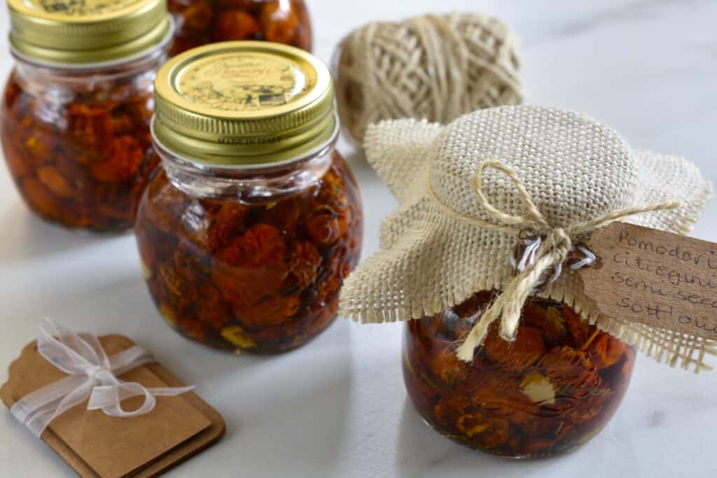 Semi-dried tomatoes in oil in jars on a worktop with packaging.