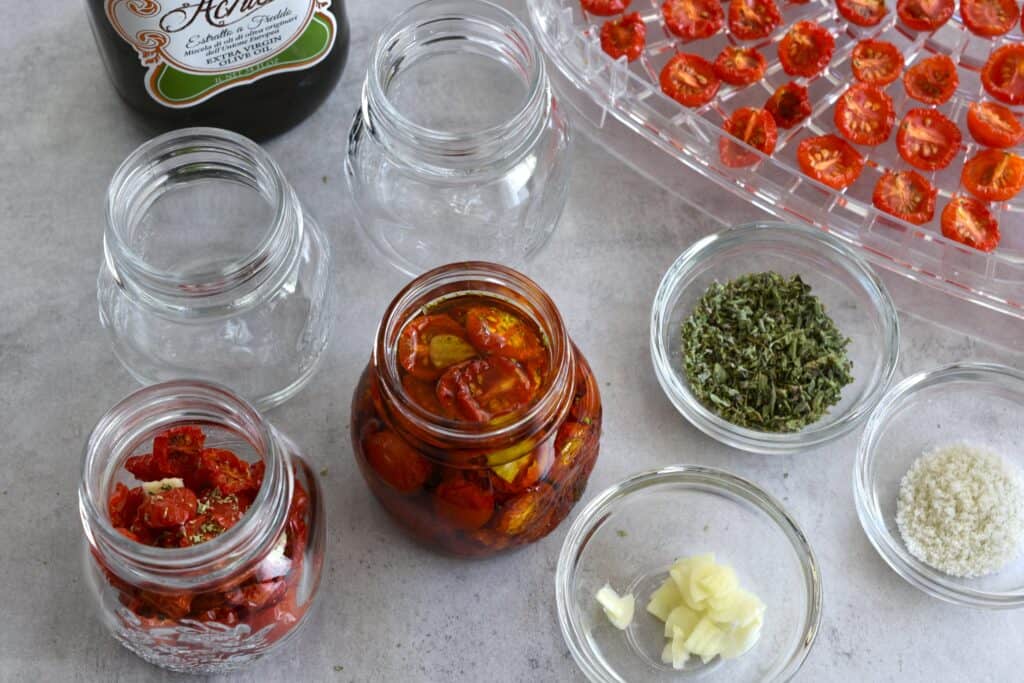 The process of jarring semi-dried cherry tomatoes with garlic, oregano, salt, and oil.