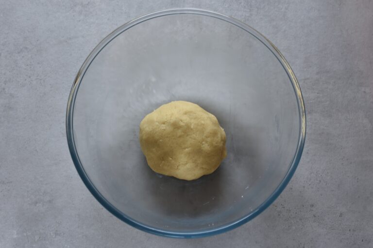 A ball of vegan shortbread biscuit dough in a glass bowl.