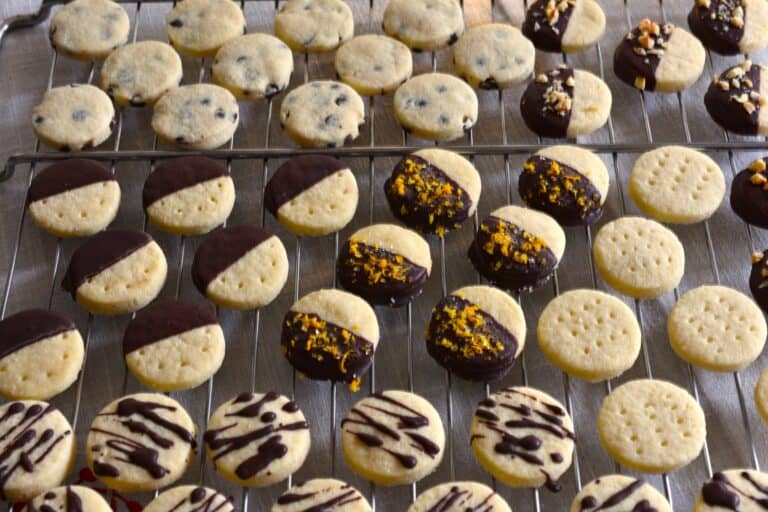 A close-up image of a vegan assortment of chocolate-dipped shortbread biscuits on an oven rack.