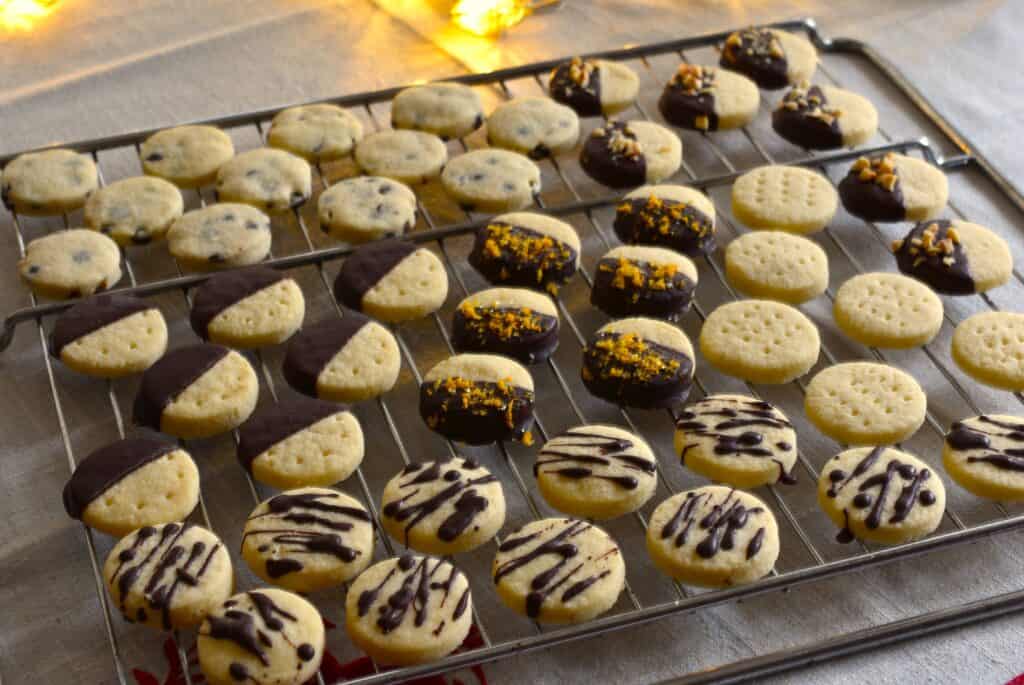 An assortment of vegan chocolate-dipped shortbread biscuits on an oven rack.