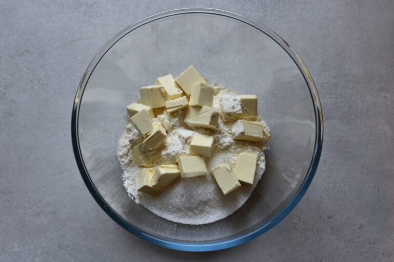 Flour, sugar, and cubes of vegan butter in a glass bowl.