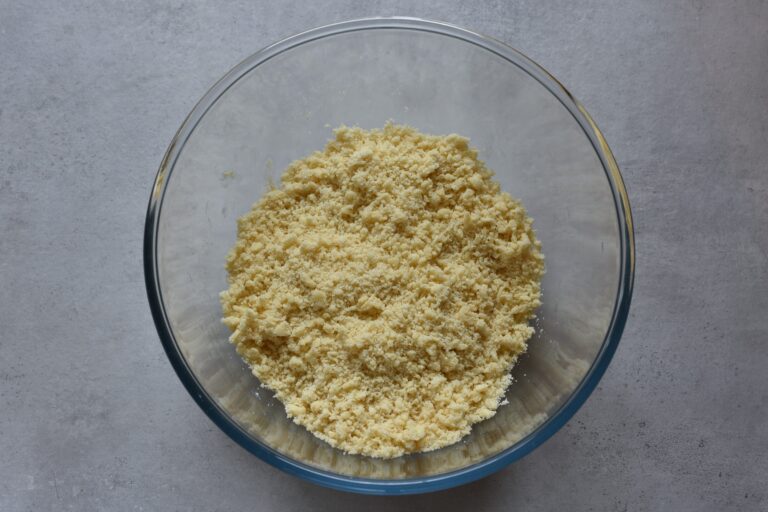 Flour, sugar, and vegan butter worked into breadcrumbs in a glass bowl.