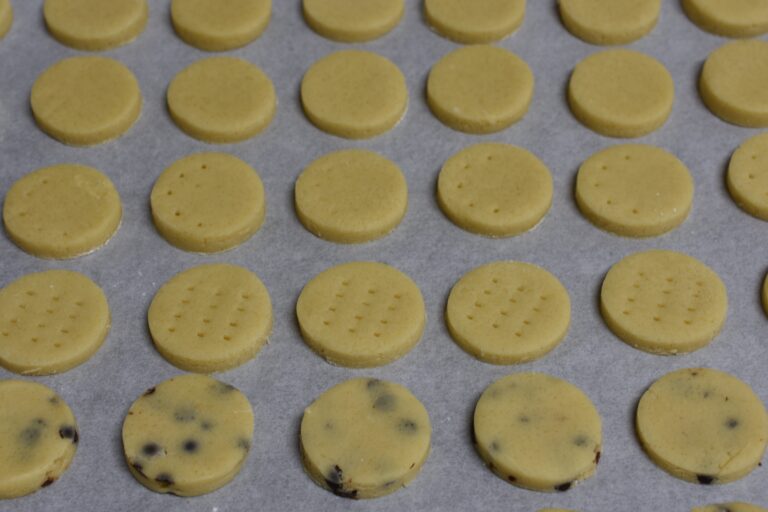 Raw shortbread biscuits on a baking tray line with parchment paper.