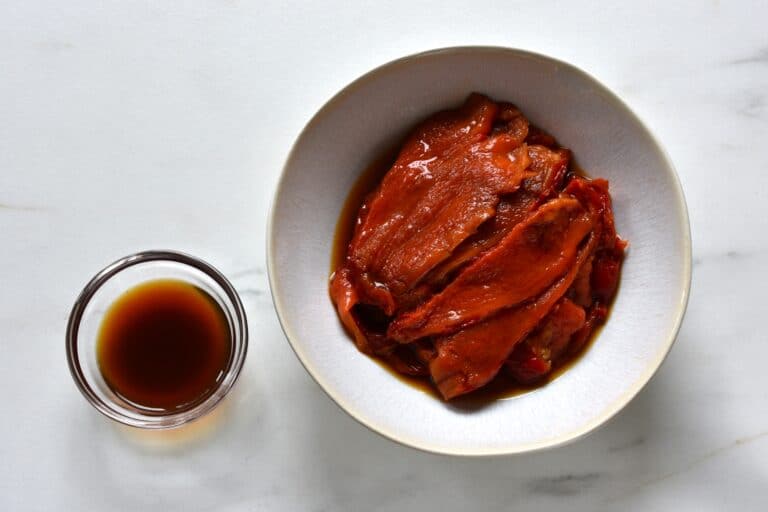 Roasted red pepper fillets and their juice in bowls.